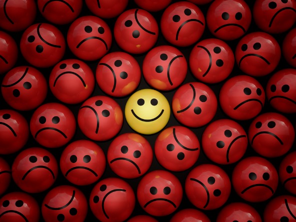 happy face on yellow ball surrounded by sad faces on red balls